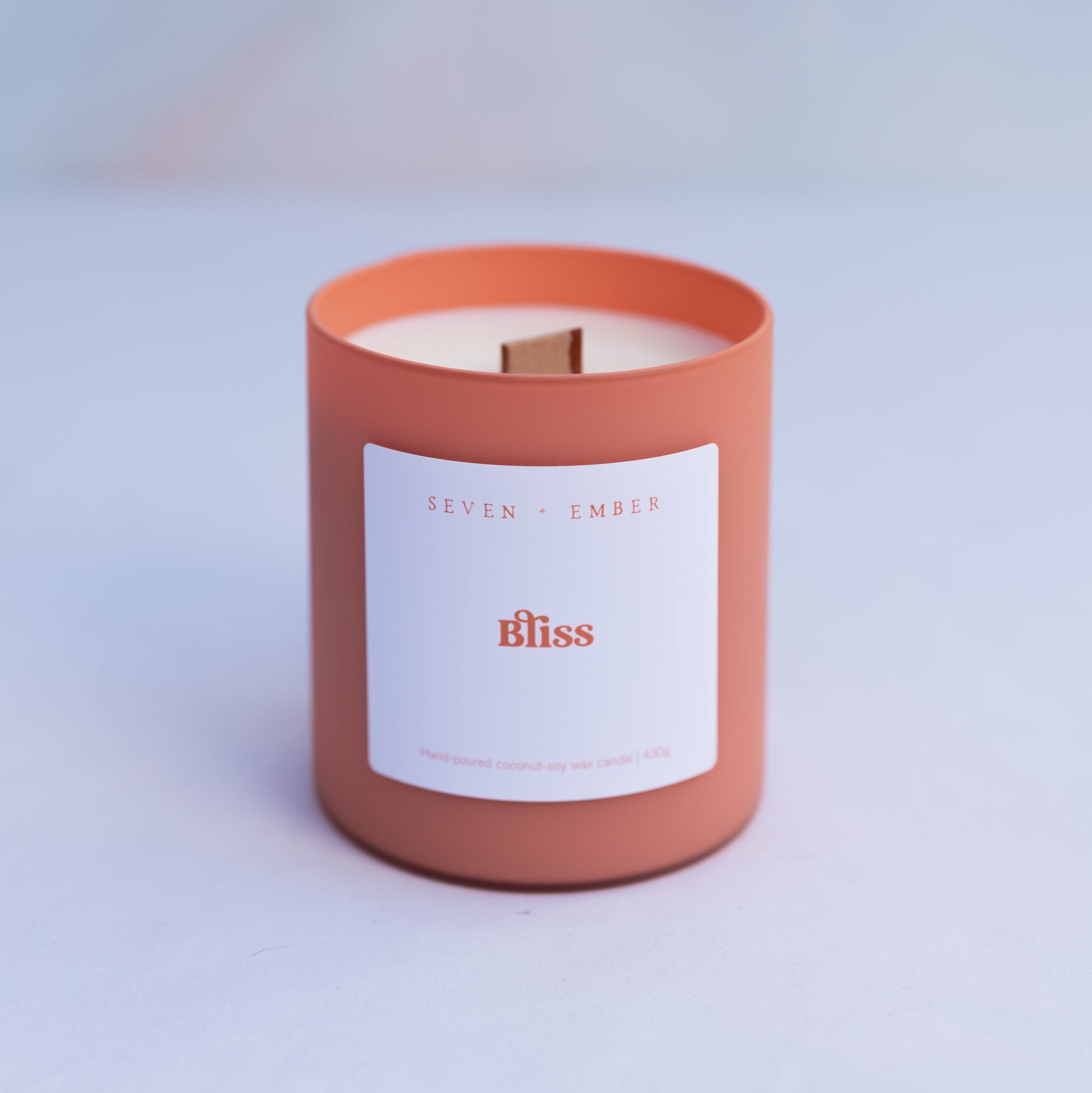 Bliss candle in an orange sorbet coloured frosted glass jar with wooden wick