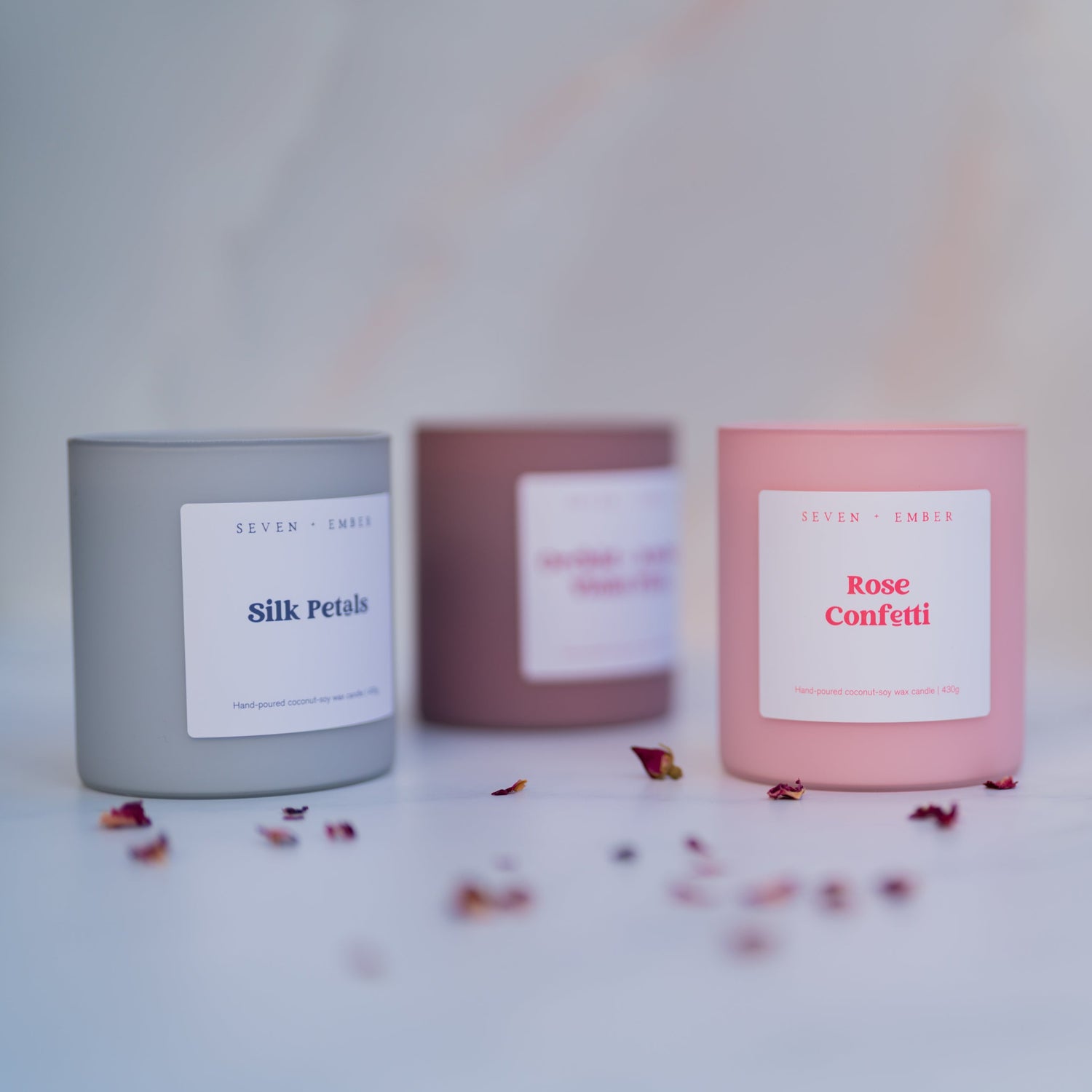 Candle with 'Rose Confetti' label on a light background with scattered petals.