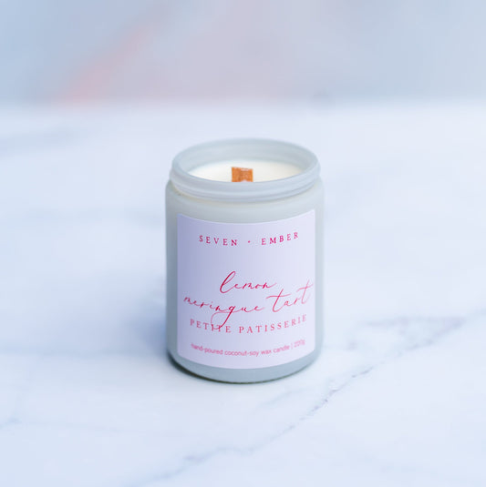 Lemon Meringue Tart candle with a wooden wick in a white screw top jar on a marble surface