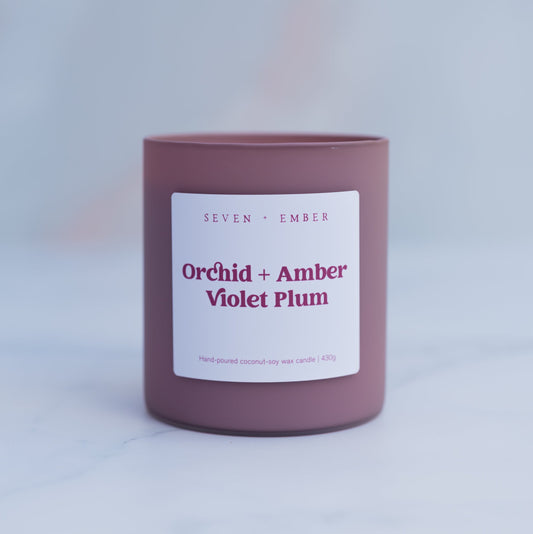 Orchid amber and violet plum in a plum coloured frosted glass vessel on a blurred marble background