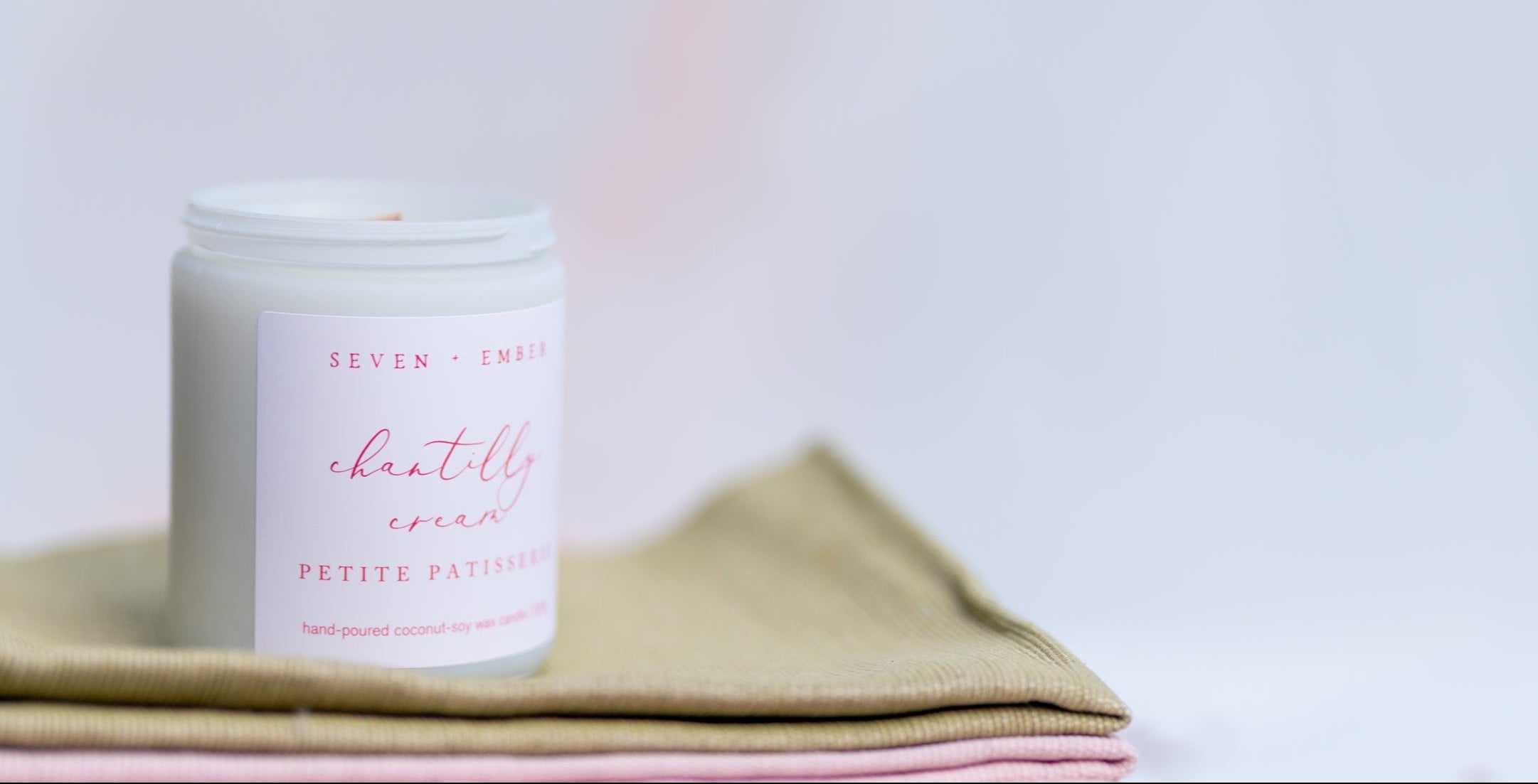 Chantilly cream candle on books with a rolling pin and fabric on a light background