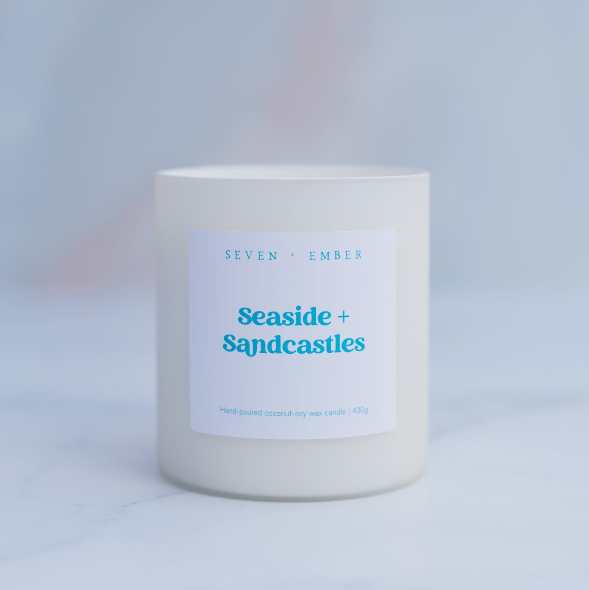 Seaside and sandcastles candle in a creamy white frosted glass vessel