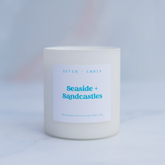 Seaside and sandcastles candle in a creamy white frosted glass vessel