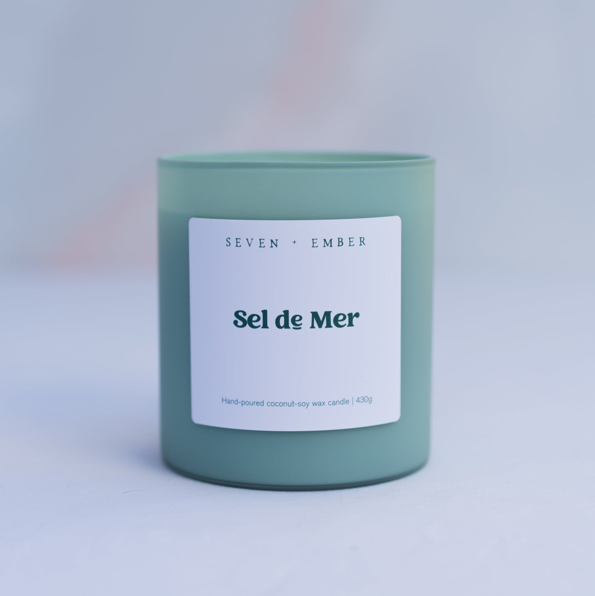 Sel de Mer scented candle in a sage green frosted glass vessel on marble background