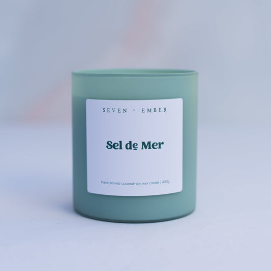 Sel de Mer scented candle in a sage green frosted glass vessel on marble background