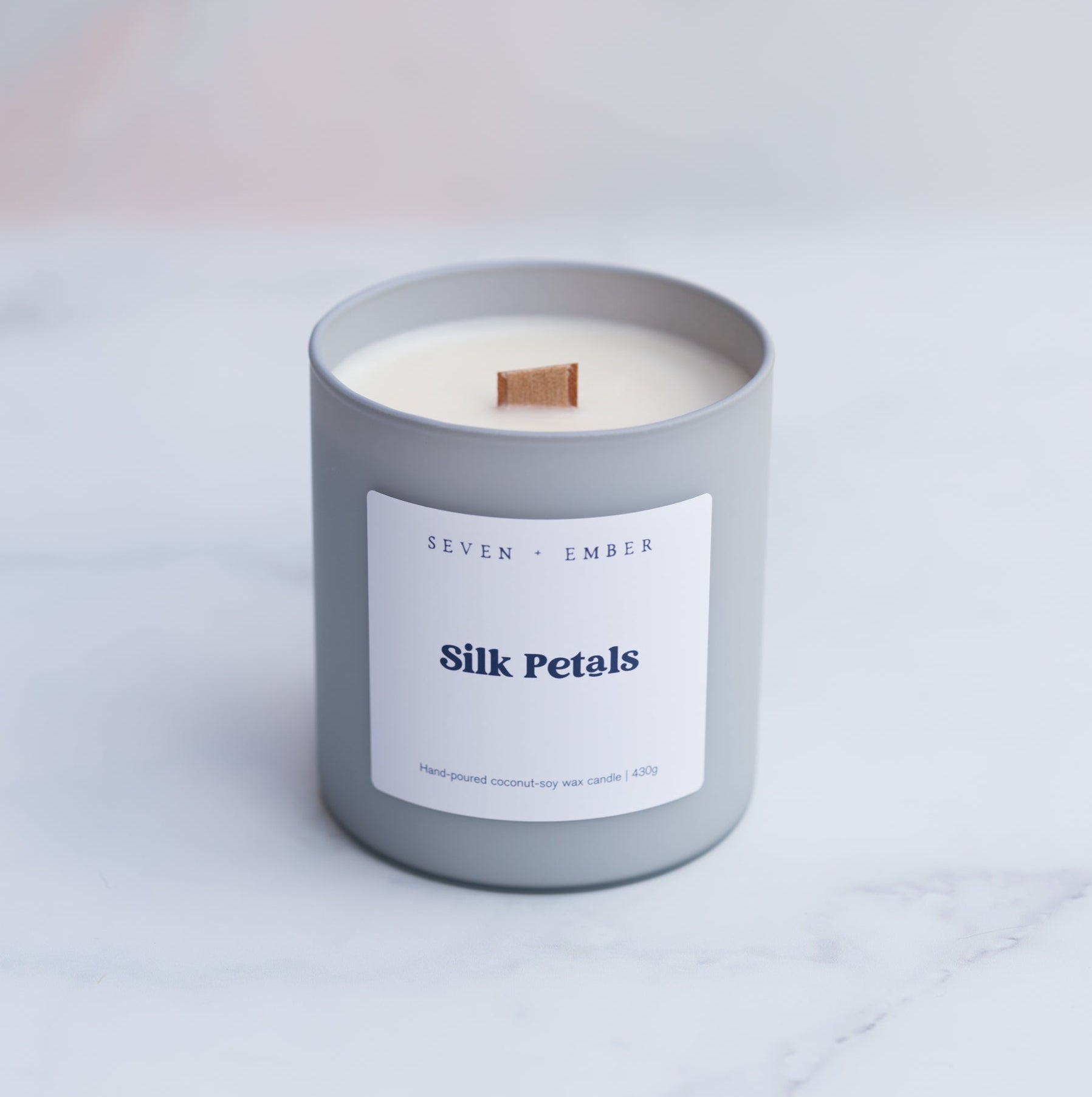 Silk petals candle with a wooden wick in a light grey frosted glass vessel