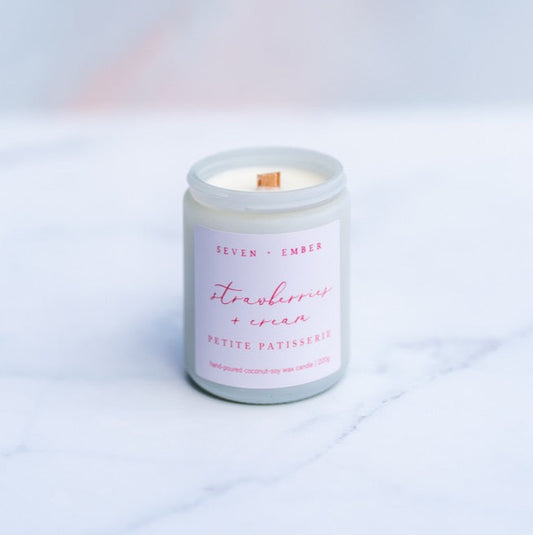 Strawberries and cream candle with wooden wick in a white screw top jar on a marble surface