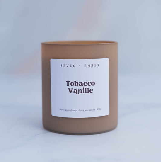 Tobacco vanilla candle in latte coloured frosted glass vessel on blurred marble background