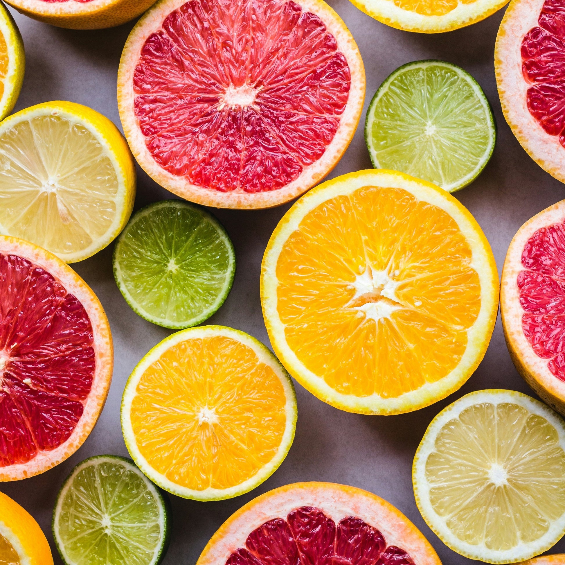 A collection of citrus slices grapefruit, lemon, lime and orange laid out on a bench top