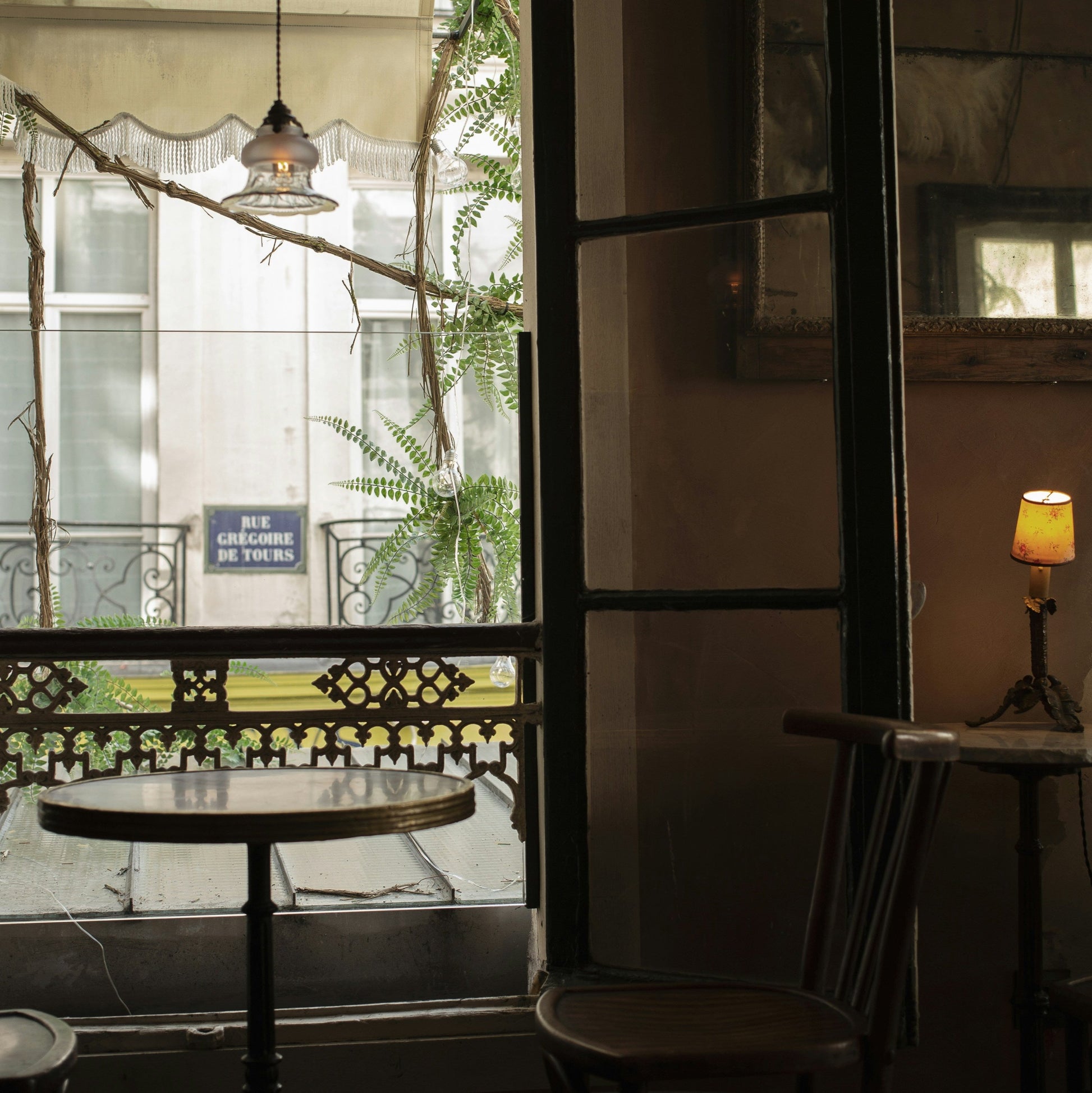 A table and chairs in front of a window in a Paris street cafe