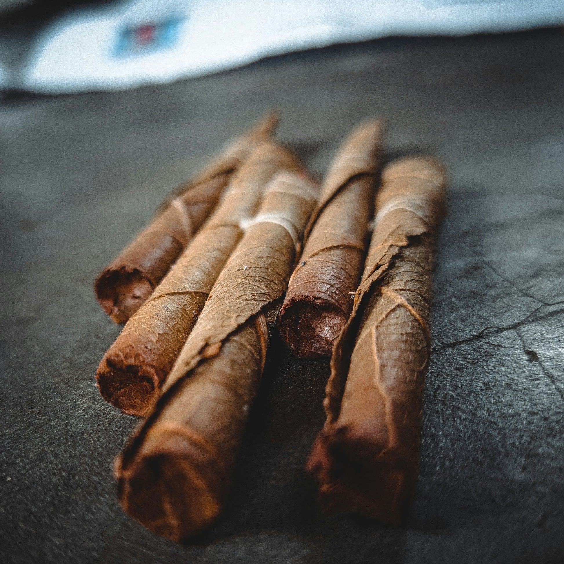 Rolled tobacco leaves on a black slate background