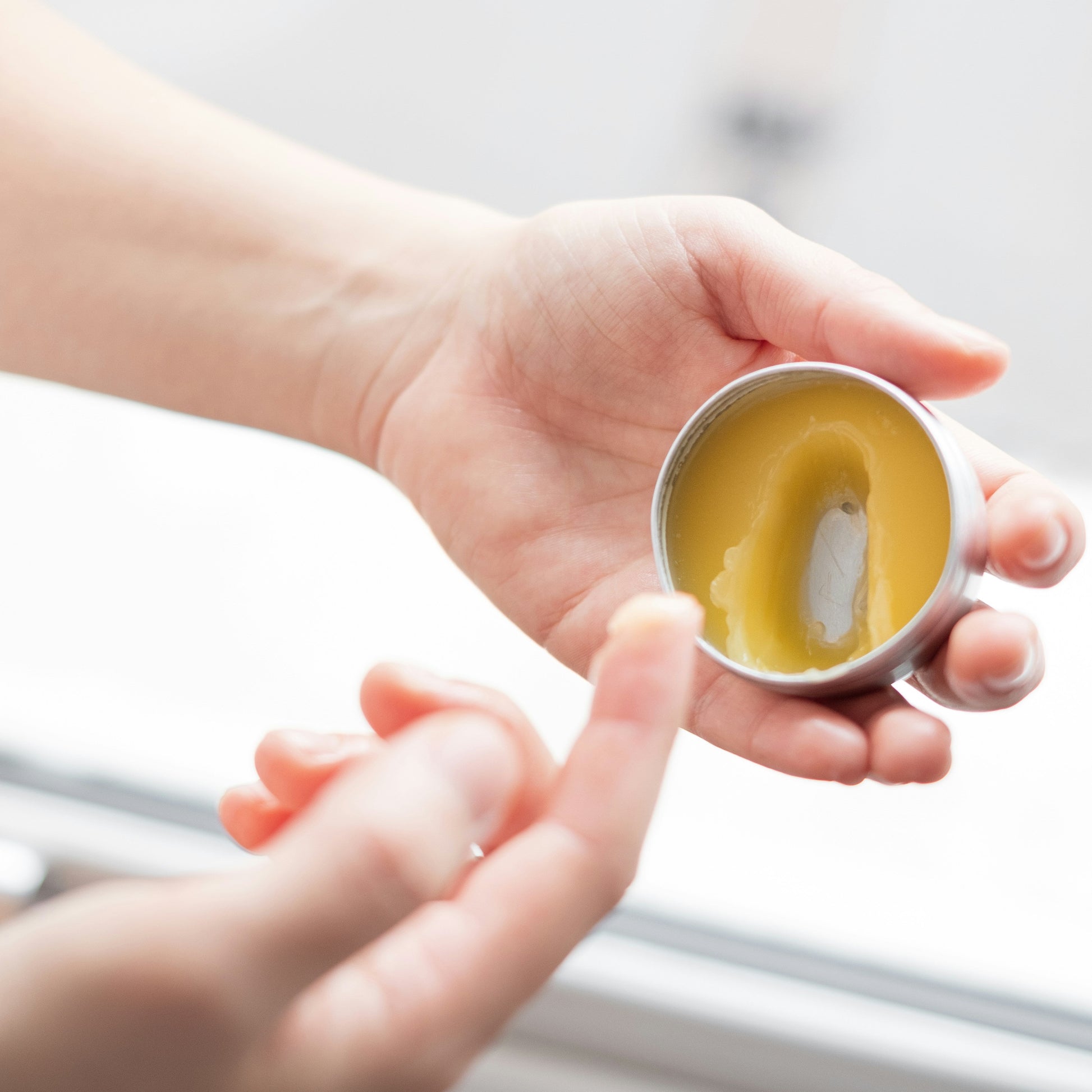Woman scraping balm from pot
