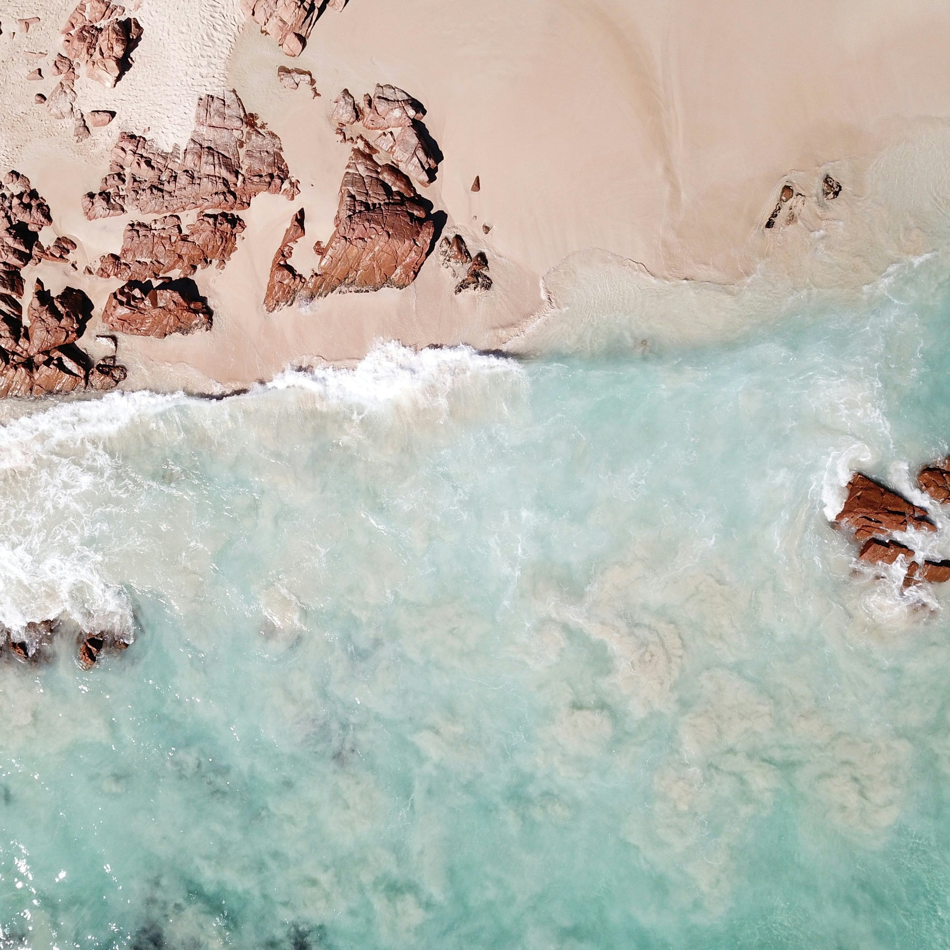 a shoreline with some rocks and crystal blue ocean water