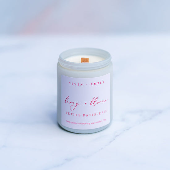 Berry and blooms candle with a wooden wick in a white screw top jar on a marble surface 