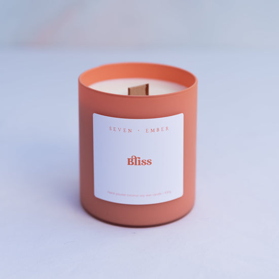 Bliss candle in an orange sorbet coloured frosted glass jar with wooden wick