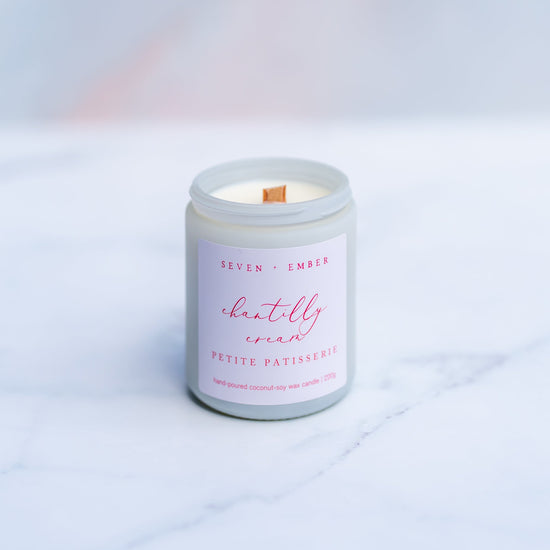 Chantilly cream candle with a wooden wick in a white screw top jar on a marble surface