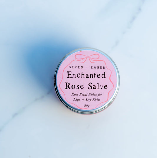 Mini jar of enchanted rose salve with a pink label on a marble surface