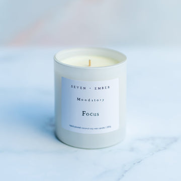 Focus mood story candle in a white vessel on a blurred marble background