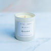 Grounded mood story candle in a white vessel on a blurred marble background