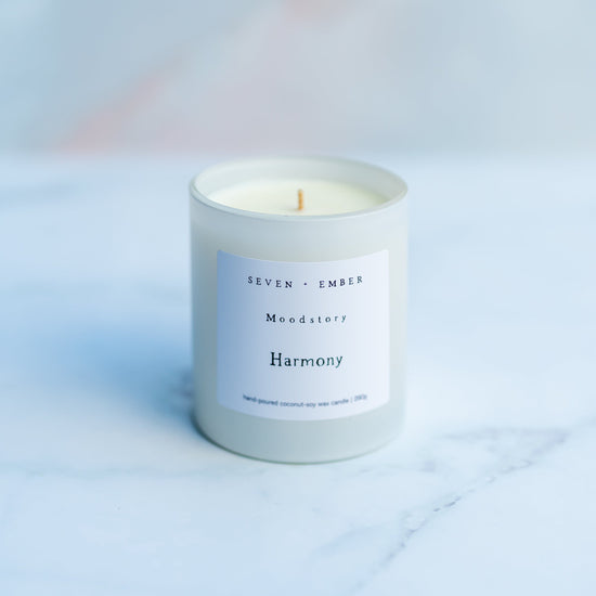 Harmony mood story candle in a white vessel on a blurred marble background