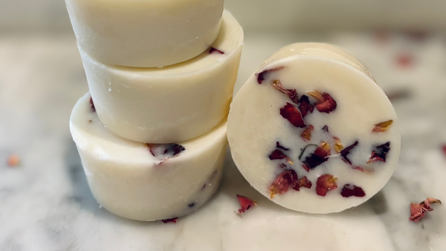 Stack of botanical wax melts with floral petals on a marble surface