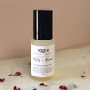 Bottle of petals and bloom essential oil room spray mist on a marble surface on a dusky pink background with rose petals scattered around