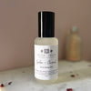 Bottle of lychee and coconut room spray mist on a marble surface with a blurred pink background