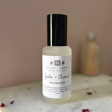 Bottle of lychee and coconut room spray mist on a marble surface with a blurred pink background