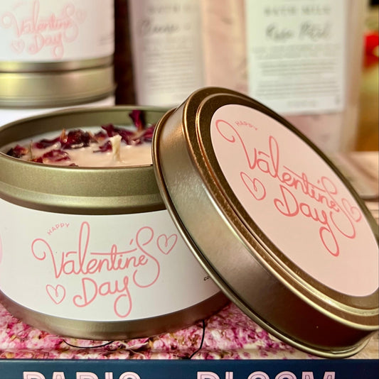Valentines Day candle iwith rose petals in a gold tin with a lid with blurred products in the background
