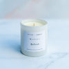 Refresh mood story candle in a white glass vessel on a blurred marble background