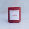 Revelry candle in a red frosted glass vessel on a blurred marble background