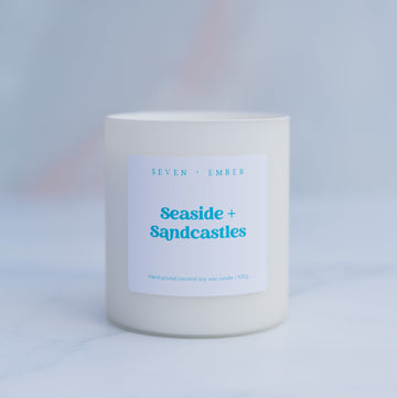 Seaside and sandcastles candle in a creamy white frosted glass vessel