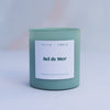 Sel de Mer scented candle in a sage green frosted glass vessel on marble background