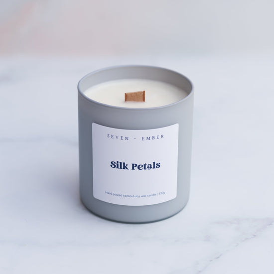 Silk petals candle with a wooden wick in a light grey frosted glass vessel