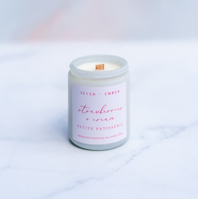 Strawberries and cream candle with wooden wick in a white screw top jar on a marble surface