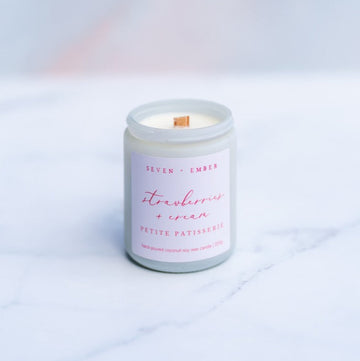 Strawberries and cream candle with wooden wick in a white screw top jar on a marble surface