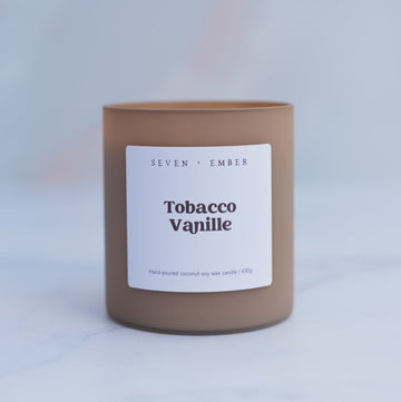 Tobacco vanilla candle in  latte coloured frosted glass vessel on blurred marble background