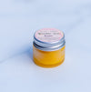 Wonder skin balm in a mini frosted jar with silver lip filled with sunshine yellow balm on a marble surface
