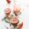 Oranges and citrus with rosemary sprigs and rose petals and a glass