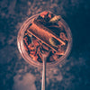 A glass jar with cinnamon, spices, star anise, cardamom pods on a blurred dark background