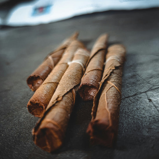Rolled tobacco leaves on a black slate background