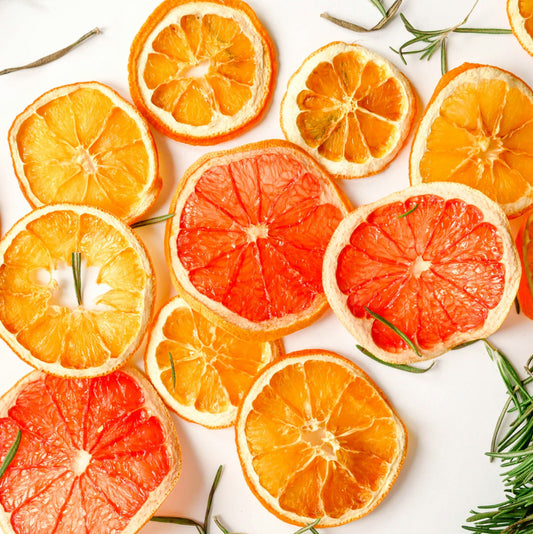 Vibrant dried orange slices with rosemary leaves on a white background