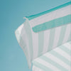 A aquamarine and white striped beach umbrella up against a backdrop of bright blue sky