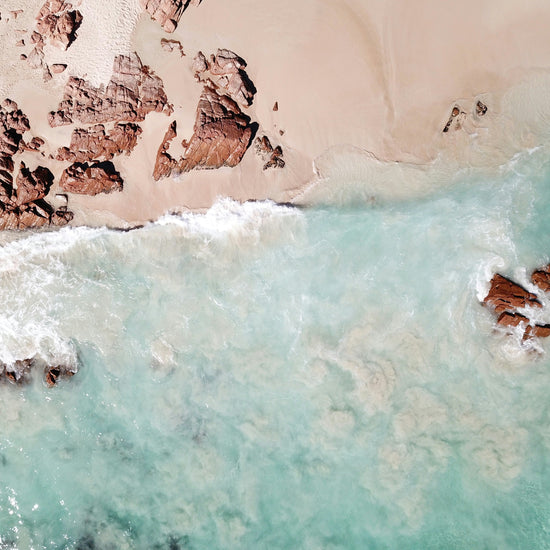 a shoreline with some rocks and crystal blue ocean water